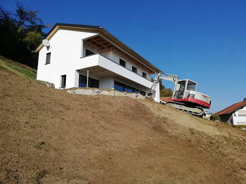 Baggerarbeiten auf Hang vor neuem modernen Haus