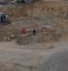 Aushubarbeiten auf einer Baustelle mit Kettenbagger und vorbereiteter Baugrube.